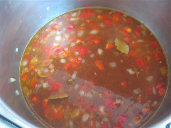 הוסיפו רוטב עגבניות, מים, עלי דפנה, כורכום,מלח, פלפל ויין לסיר, ערבבו והביאו לרתיחה.
