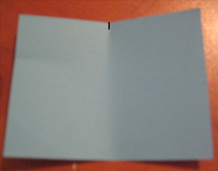 קפלו את הנייר לחצי לרוחבו ו'צבטו' את הקיפול שעשיתם בכדי לסמן את מרכז הנייר.