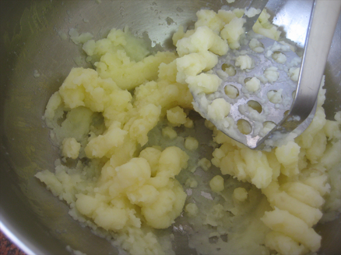 מעכו את תפוחי האדמה בעזרת מועך תפוחי אדמה בקערה או בבלנדר.