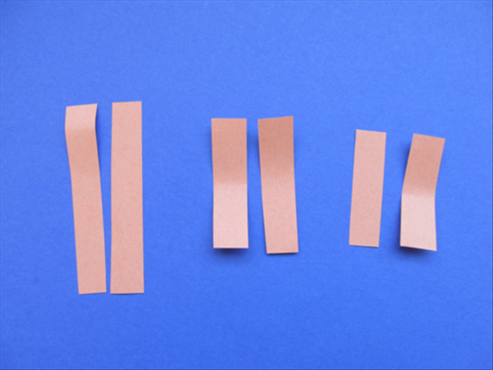 חתכו רצועות  נייר בעובי 1.5 ס'מ.
2 רצועות באורך 5 ס'מ.
2 רצועות באורך 6 ס'מ.
2 רצועות באורך 9 ס'מ.

המדידות האלו הם בשביל לבבות קטנים לתליה.
תוכלו להכין רצועות ארוכות יותר ועבות יותר, רק עשו אותם באותם פרופורציות.